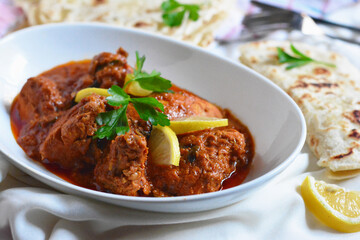 Butter Chicken An Indian dish of chicken, butter and hot sauce garnished with lemon and parsley and served with chapatti bread or puri bread
food photography