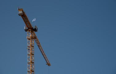 Naklejka premium Yellow Industrial construction crane against blue sky. Industrial development, building construction