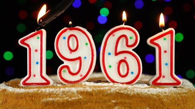 Birthday cake with white burning candles in the form of number 1961
