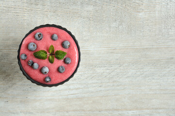Fresh mixed berry smoothie garnished with frozen black currants and mint in a baking dish. An alternative to a healthy diet in favor of fresh vitamins. Top view with copy space