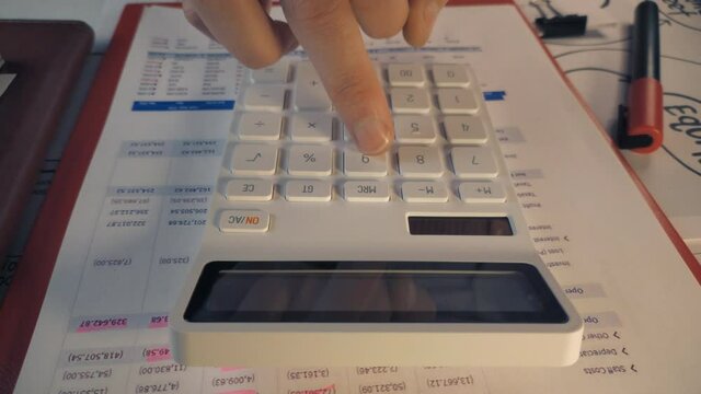 Person using a basic standard white calculator to create financial reports close up stock footage