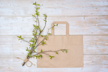 bouquet of green willow twigs and a paper bag for goods on a wooden background. There is room for text.