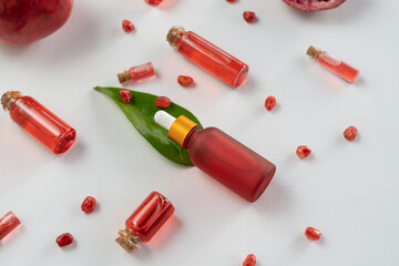 Red dropper bottles of pomegranate serum or oil for face and body lying on a white table