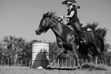 Western rodeo lifestyle shows cowgirl barrel racing in outdoor arena. - obrazy, fototapety, plakaty