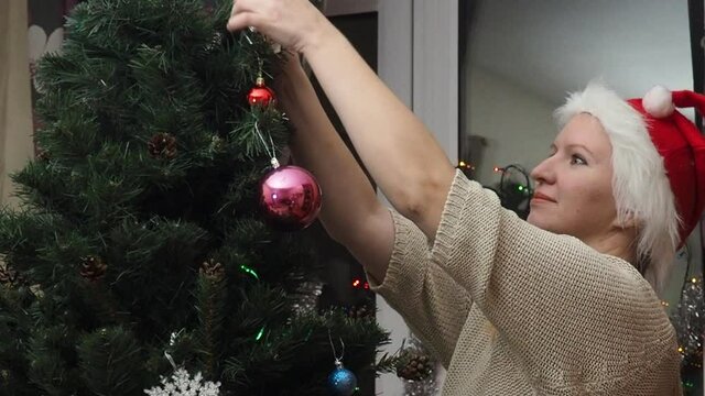 Family decorating a Christmas tree with boubles in the living room. mom and daughter decorate the tree with different toys home, family holidays, happy new year and christmas