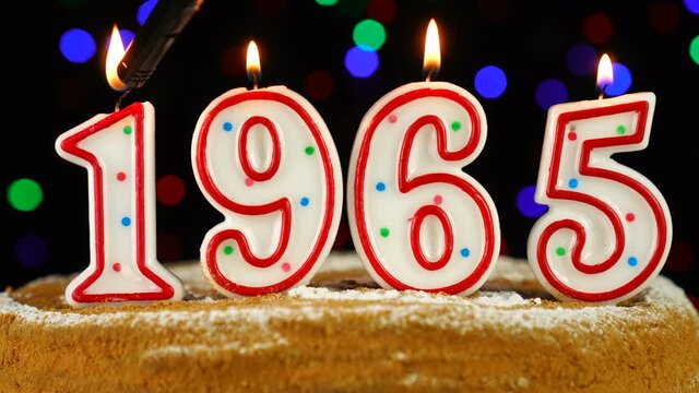 Birthday cake with white burning candles in the form of number 1965