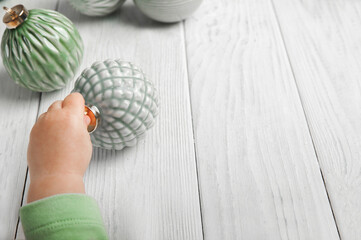 Christmas green balls from recycled glass and child's hand. Scandinavian Botanical New Year...