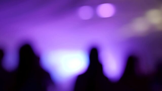 Defocused view of great wedding party with silhouettes of people dancing on the dancefloor.