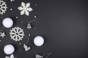White Christmas decorations lie on a black background. Copy space. Christmas card mockup