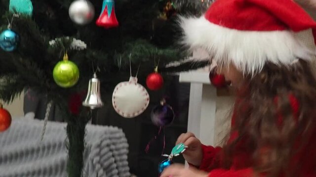 Family decorating a Christmas tree with boubles in the living room. mom and daughter decorate the tree with different toys home, family holidays, happy new year and christmas