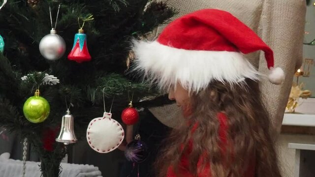 Family decorating a Christmas tree with boubles in the living room. mom and daughter decorate the tree with different toys home, family holidays, happy new year and christmas