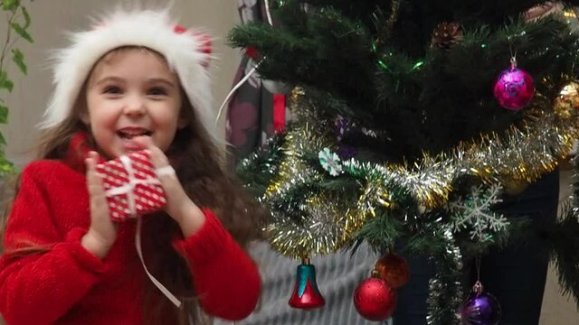 Family decorating a Christmas tree with boubles in the living room. mom and daughter decorate the tree with different toys home, family holidays, happy new year and christmas