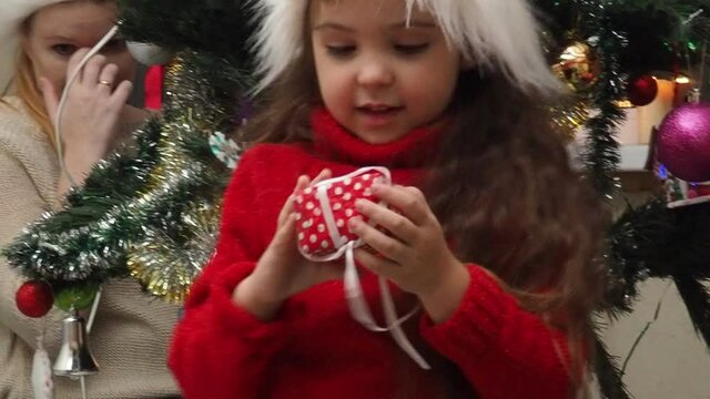 Family decorating a Christmas tree with boubles in the living room. mom and daughter decorate the tree with different toys home, family holidays, happy new year and christmas