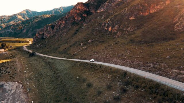 White car drives through narrow road in the mountains. Drone footage