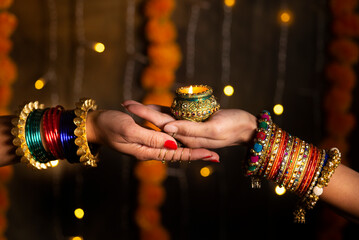 Woman hand's with bangles holding Diya 