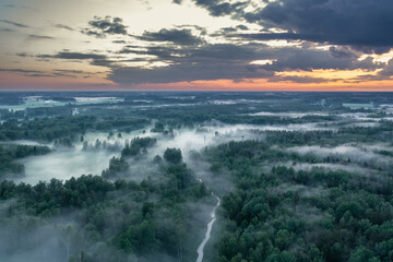 Aerial view of foggy forest at colorful sunset