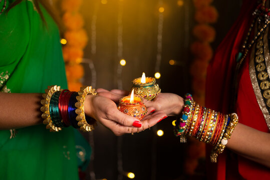 Woman hand's with bangles holding Diya 