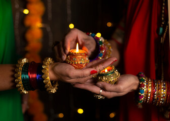 Woman hand's with bangles holding Diya