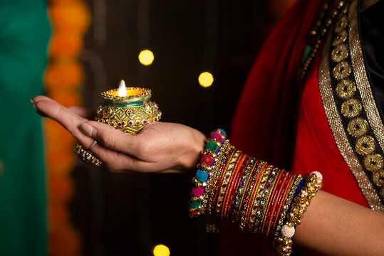 Woman hand's with bangles holding Diya 