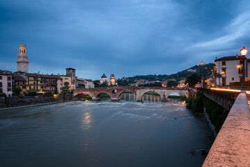 Fototapeta na wymiar City landscape with the old town buildings along the bank of the Adige river and the famous Stone Bridge (Ponte di Piettra) at sunrise, Verona, Veneto Region, Italy