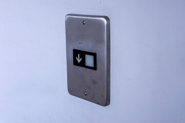 Angled view of a Down elevator button panel on a white wall inside a business building