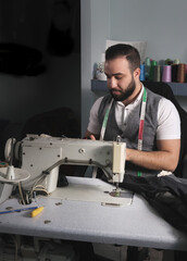 Middle Eastern young man working at his tailor shop. Small business or self-employed concept
