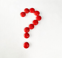 question mark with red Small wooden objects on white paper.