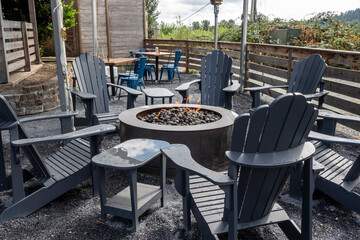 Close up view of adirondack chairs circling a fire pit filled with stones inside an outdoor patio area at a restaurant