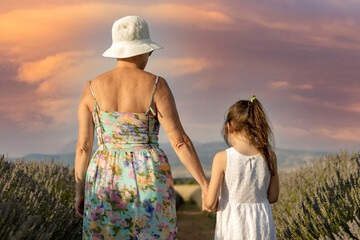 grandmother and little girl walking in beautiful field