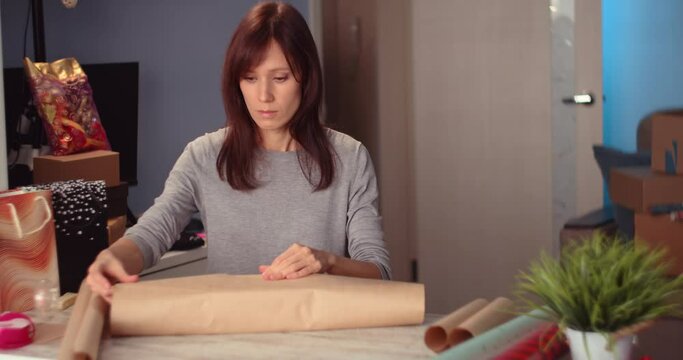 Wrapping holyday gift. Woman Hands decorating stylish gift in craft paper on table in home