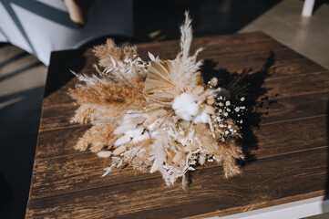 Wedding bouquet lying on a wooden table made of reeds, wildflowers, largus, cotton. © shchus