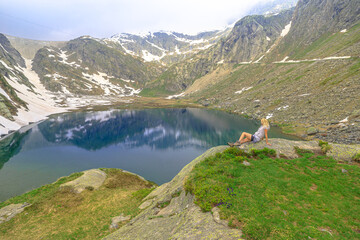 Swiss reservoir in Maggia Valley of Ticino canton of Switzerland with Cavagnoo dan. Tourist woman resting during the trekking around the Lago Bianco lake or White Lake.