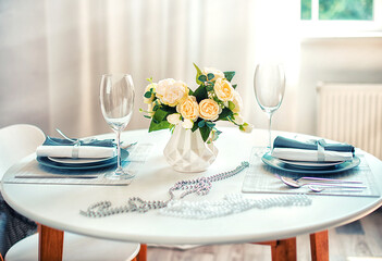 Beautiful table setting in light colors in the room by the window