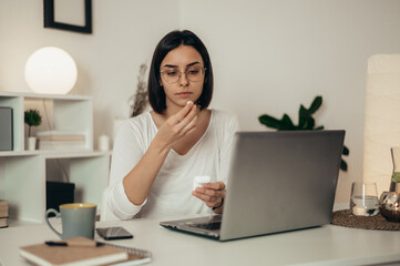 Beautiful woman using airpods and a laptop while working from home