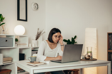 Woman feeling tired and stressed while using a laptop and working from home