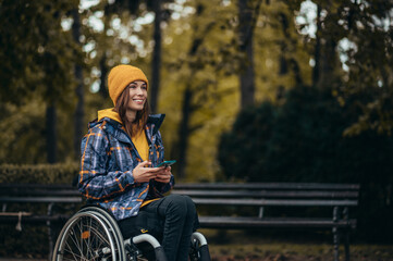 Fototapeta na wymiar Woman with disability using a smartphone while out in the city park