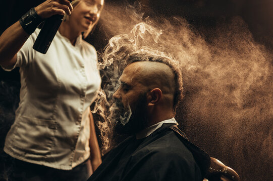 Young bearded man with a mohawk getting haircut by hairdresser and smoking a cigarette - Powered by Adobe