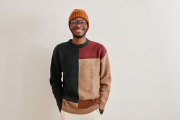 Minimal waist up portrait of smiling African-American man wearing knit sweater and hat, copy space