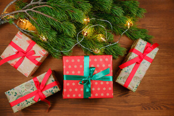 Christmas presents on a wooden table with branch of christmas tree and xmas lights