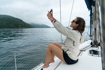 Woman holding a mobile phone on a sailboat