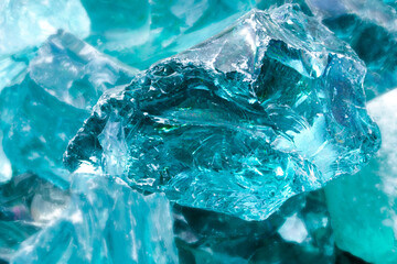 Background with ice cubes in aquamarine light. Pieces of crushed blue ice glass cracks background texture. close-up frozen water
