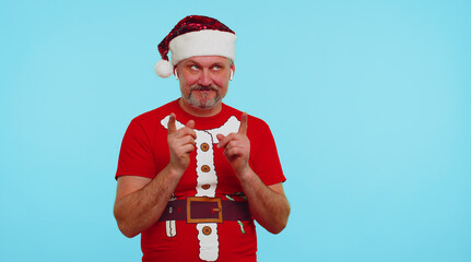 Man in Christmas t-shirt listening music via earphones, dancing disco fooling around having fun expressive gesticulating hands. Elderly old guy isolated on blue background. Happy New Year celebration