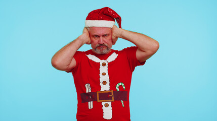 Dont want to hear and listen. Frustrated annoyed irritated man wears red New Year t-shirt covering ears and gesturing no, avoiding advice ignoring unpleasant noise loud voices. Merry Christmas holiday