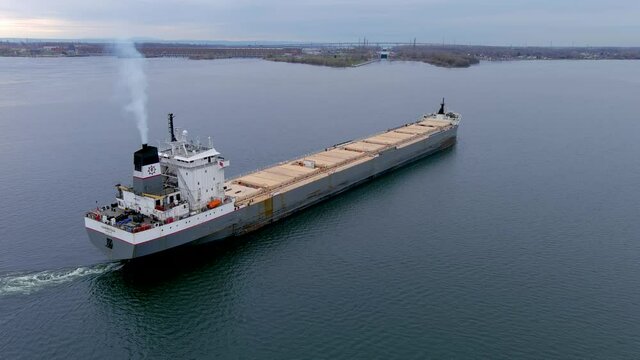 A bulk carrier ship navigates the St Lawrence Seaway as it approaches the Beauharnois Canal near Montreal, Quebec. High quality 4K aerial view.
