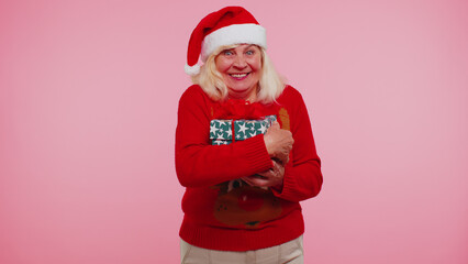 Elderly senior lovely grandmother woman wears red New Year sweater and deer antlers smiling looking at camera. Granny isolated on pink studio wall background. Happy Christmas celebration merry holiday