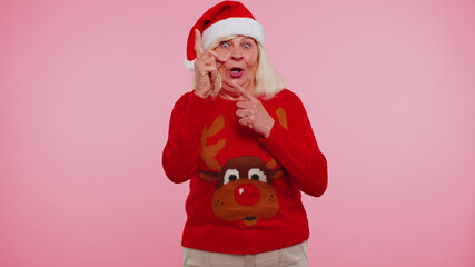 Eureka. Mature grandmother in Christmas sweater with deers make gesture raises finger came up with creative plan feels excited with good idea, inspiration motivation on pink background. Happy New Year