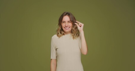 Giggling young girl showing with fingers small prices gesture enjoying sale and discount on green studio background - Powered by Adobe
