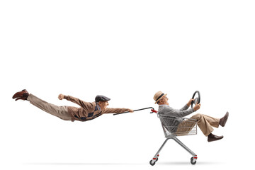 Senior flying attached to a shopping cart with an elderly man inside holding a steering wheel