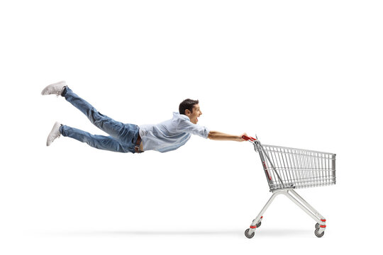 Full length shot of a casual young man flying and holding an empty shopping cart
