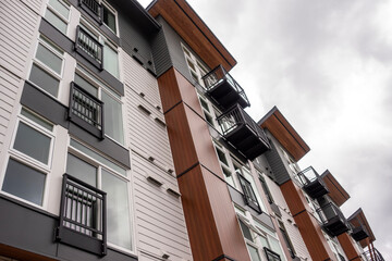 Low angle view of a Seattle apartment building, with wood paneling features and black iron...